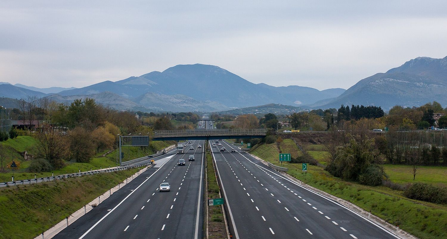 Un tratto di autostrada italiana che attraversa la campagna con le colline sullo sfondo
