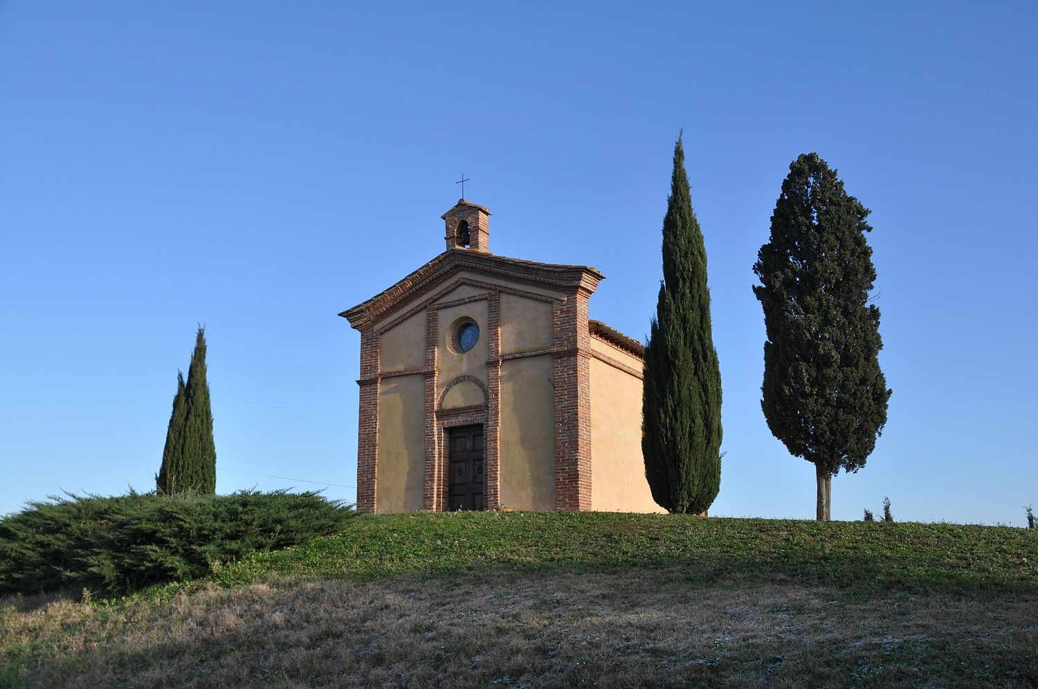 La Cappella di Baccoleno con i suoi cipressi, sulle colline verdi delle crete senesi